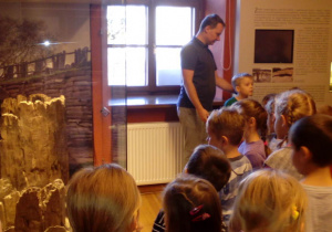 Dzieci w muzeum oglądają eksponaty archeologiczne.